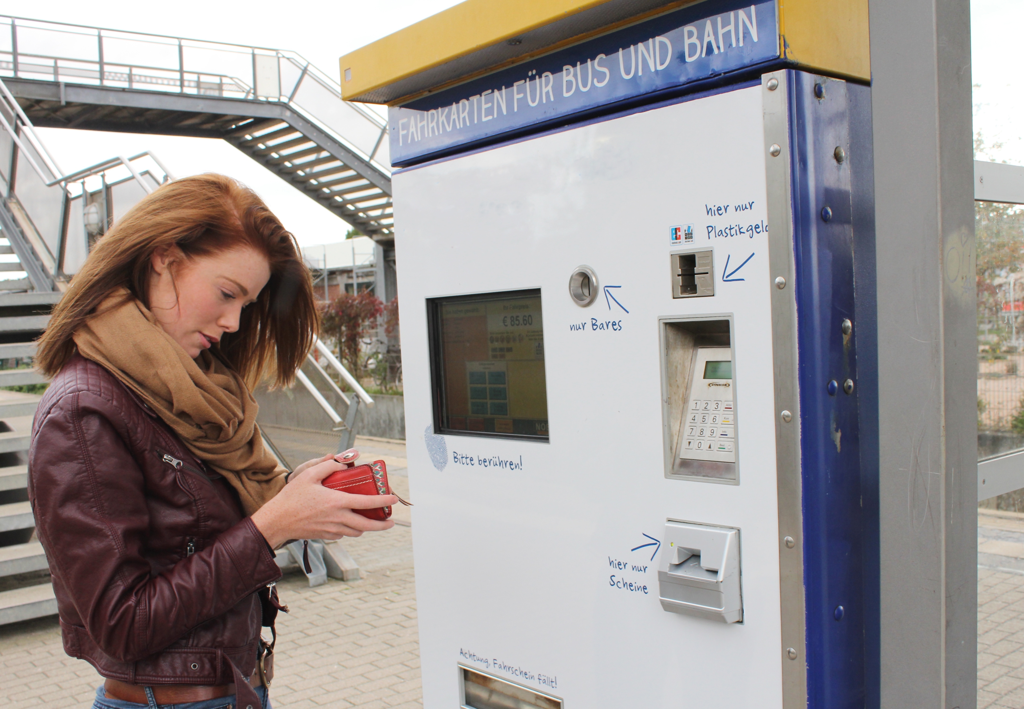 Pendlerin steht vor einem Fahrkartenautomaten.