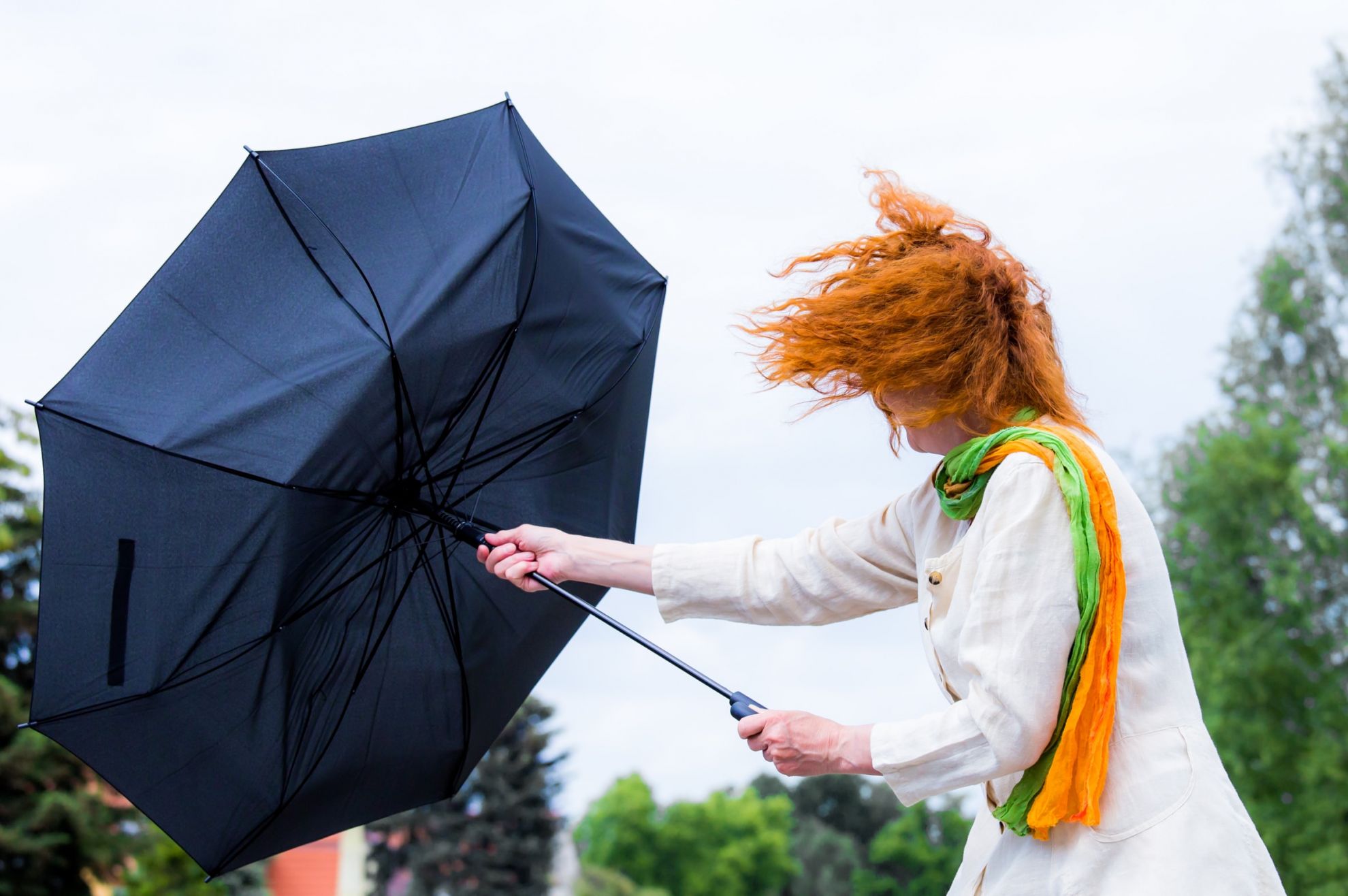 Frau mit Regenschirm bei Sturm.