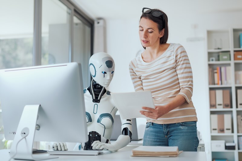 Ein humanoider Roboter und eine Frau arbeiten gemeinsam in einem Büro.