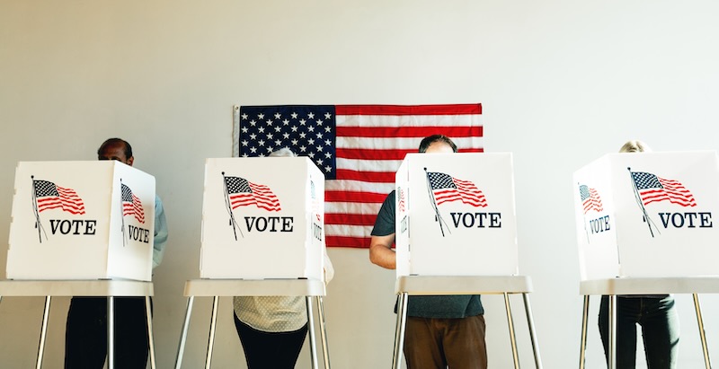 Ein Wahllokal in den USA mit mehreren Personen in Wahlkabinen.